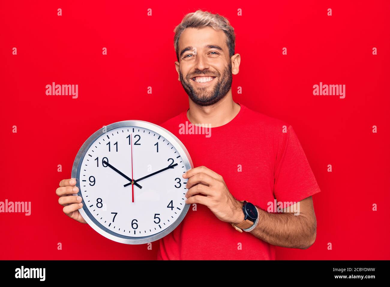 Young handsome blond man with beard doing countdown using big clock ...