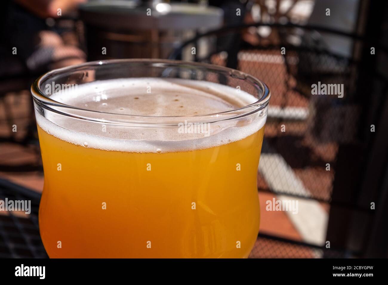 Close up of a sour beer in a clear beer glass. The liquid is sitting on