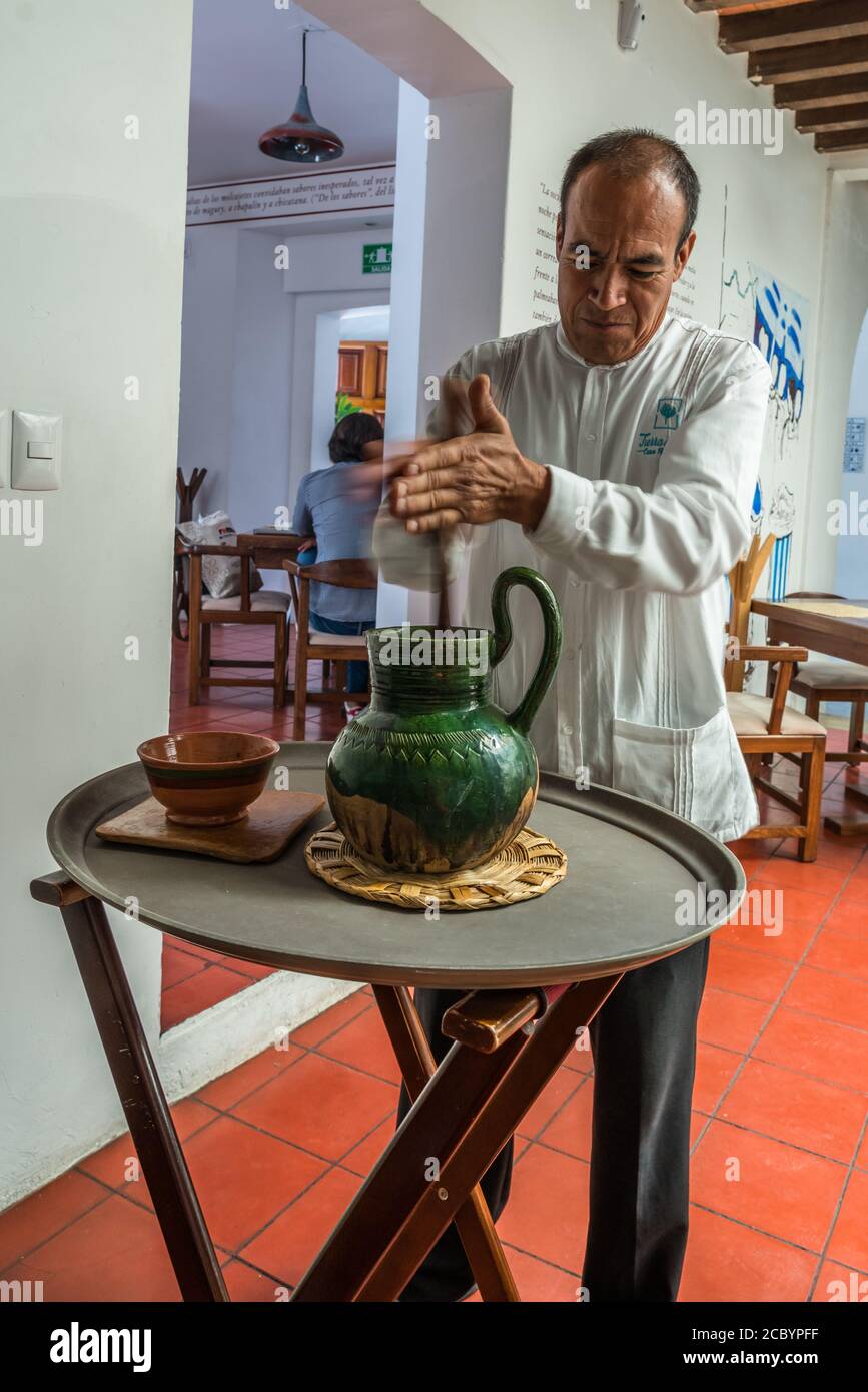 This waiter is preparing Oaxacan hot chocolate, mixing it by spinning a carved wooden molinillo in the pitcher of hot chololate to make it frothy.  Oa Stock Photo