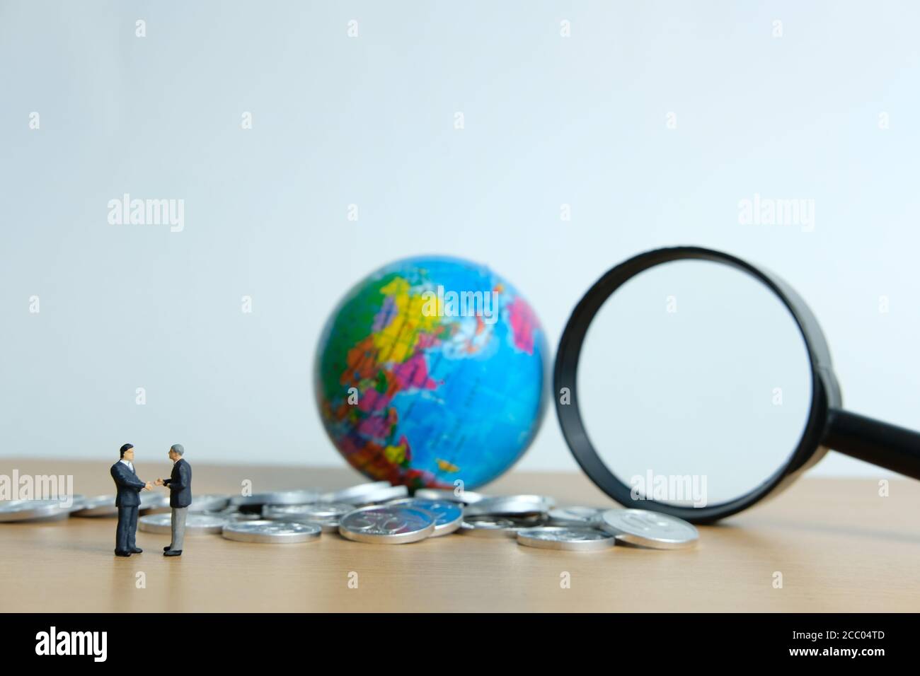 Miniature people business concept -Global trade partnership, with businessman, coin stack and globe Stock Photo