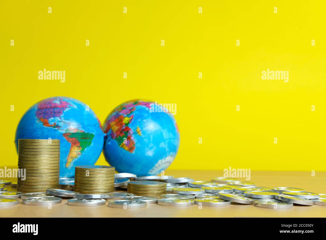 Global trade and financial concept - decreasing stack of coin in front of earth globe Stock Photo