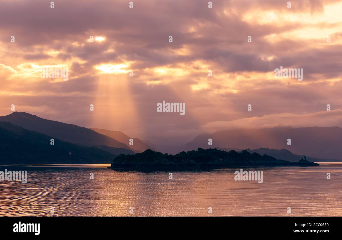 Inner Hebrides, Scotland.  Sunrise as sunrays burst through the clouds lighting up a  mountain range.  Concept: Tranquility. landscape. Space for copy Stock Photo