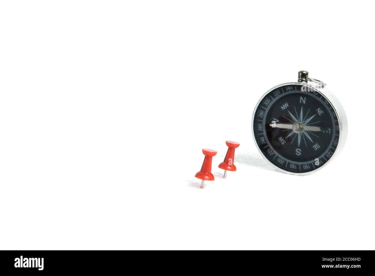 Two embedded red thumbtack / pushpin with compass isolated on white background Stock Photo