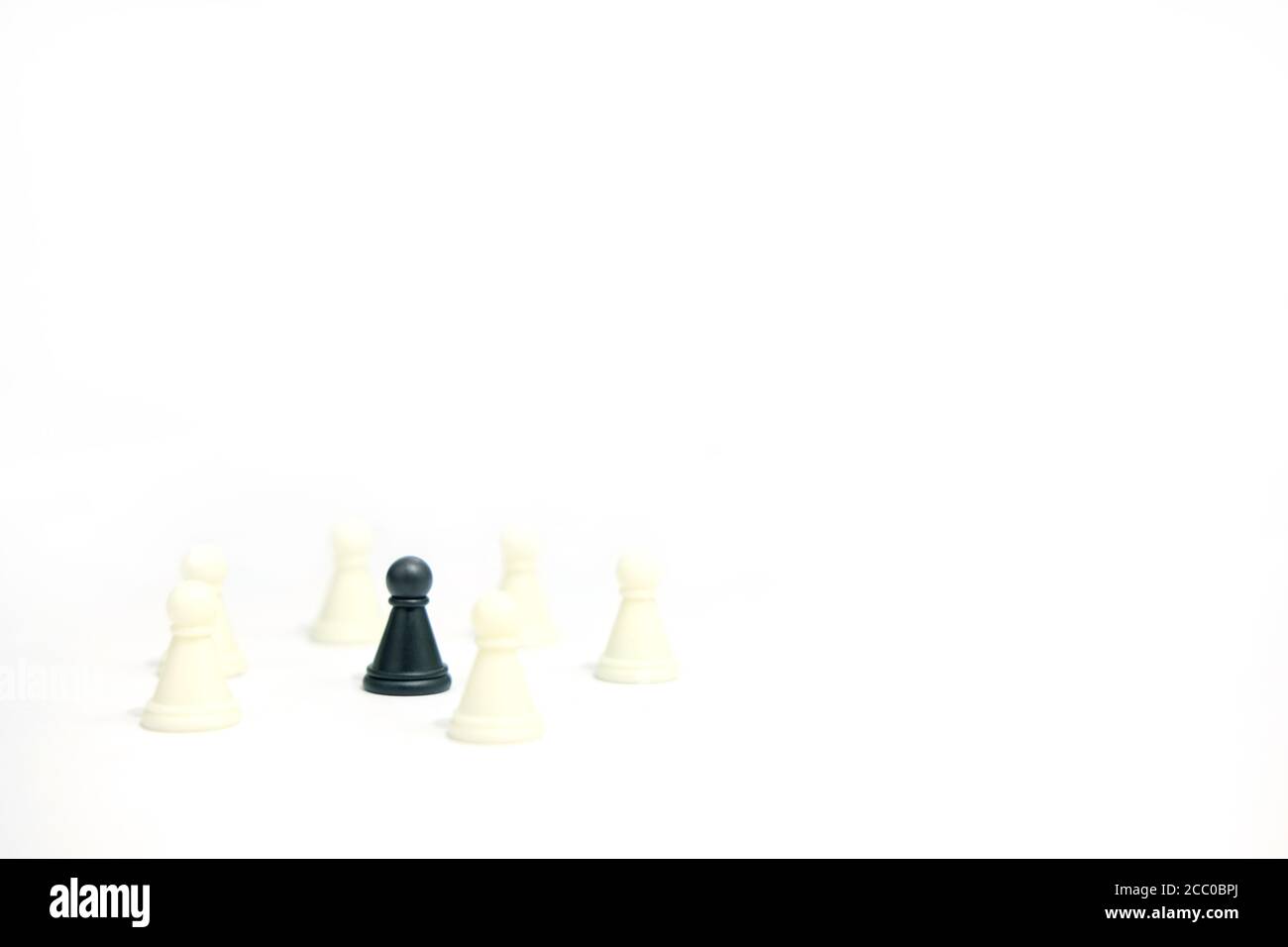 Miniature business strategy concept - black pawn standing between chess piece - front view Stock Photo