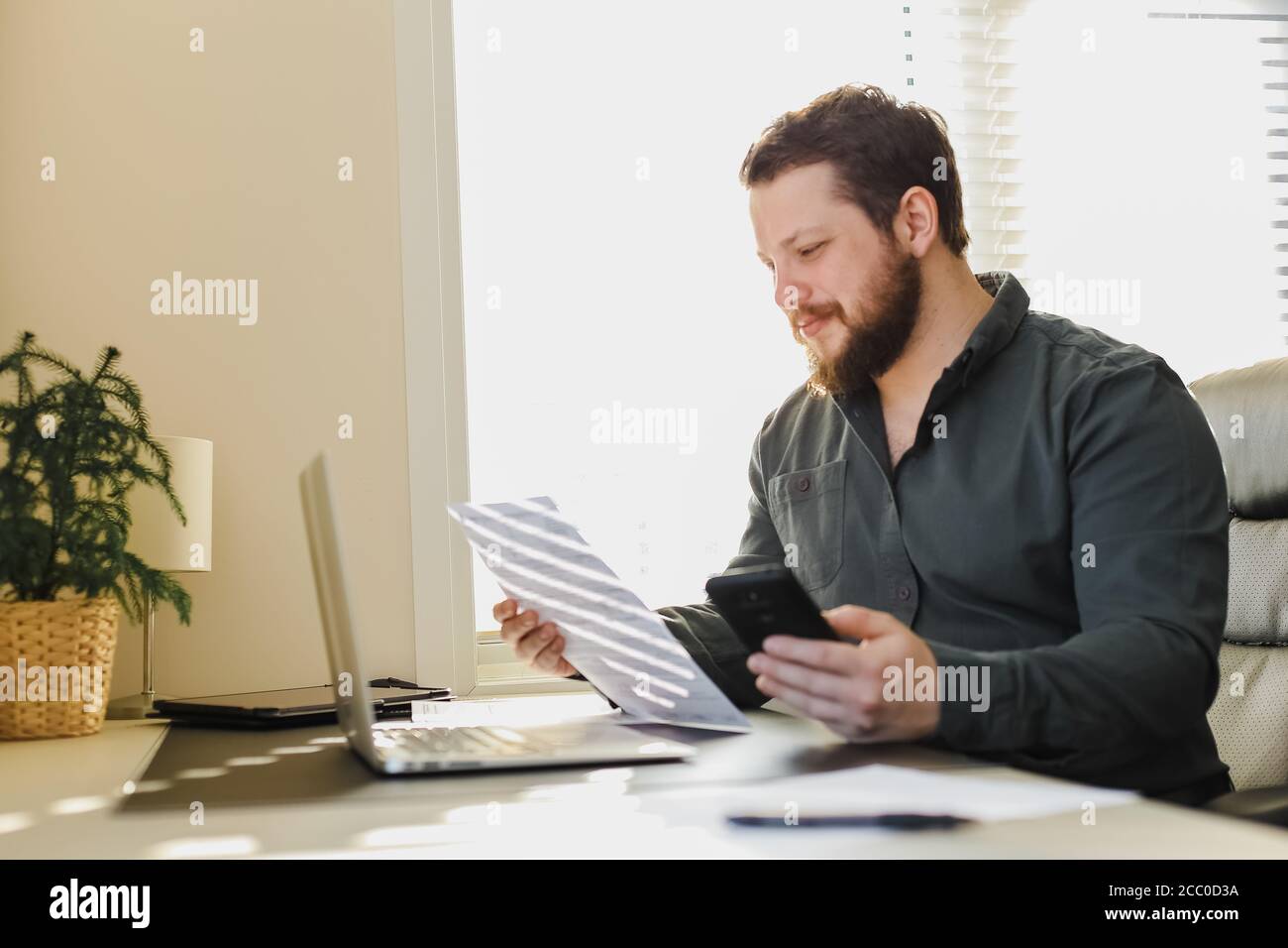 Caucasian manager working with documents, smartphone and laptop. Stock Photo