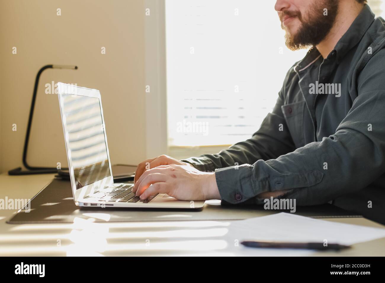 Male bloger writing article on laptop at office. Stock Photo