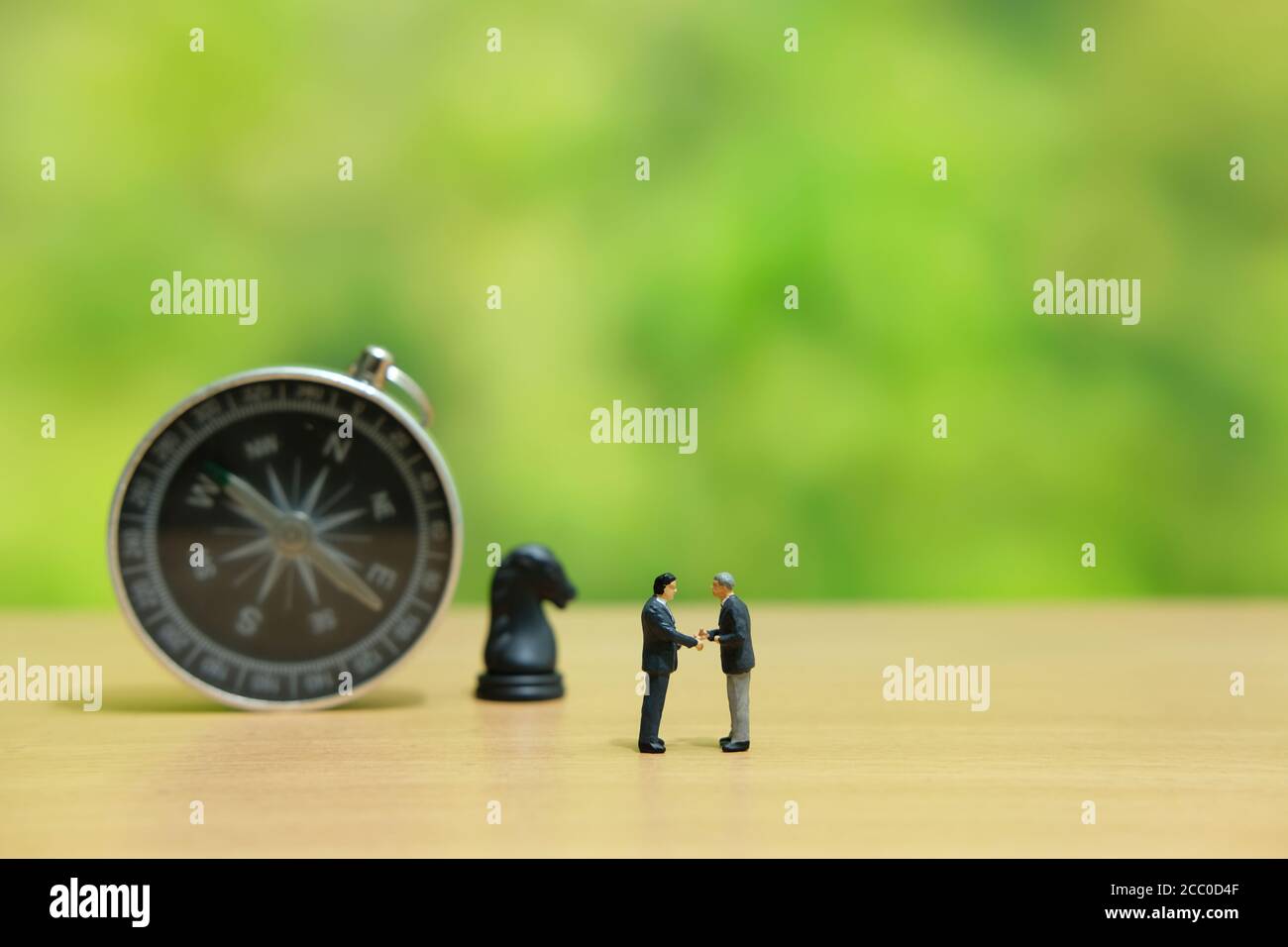 Miniature people strategic concept - businessman make partnership strategy in front of horse knight pawn and compass Stock Photo
