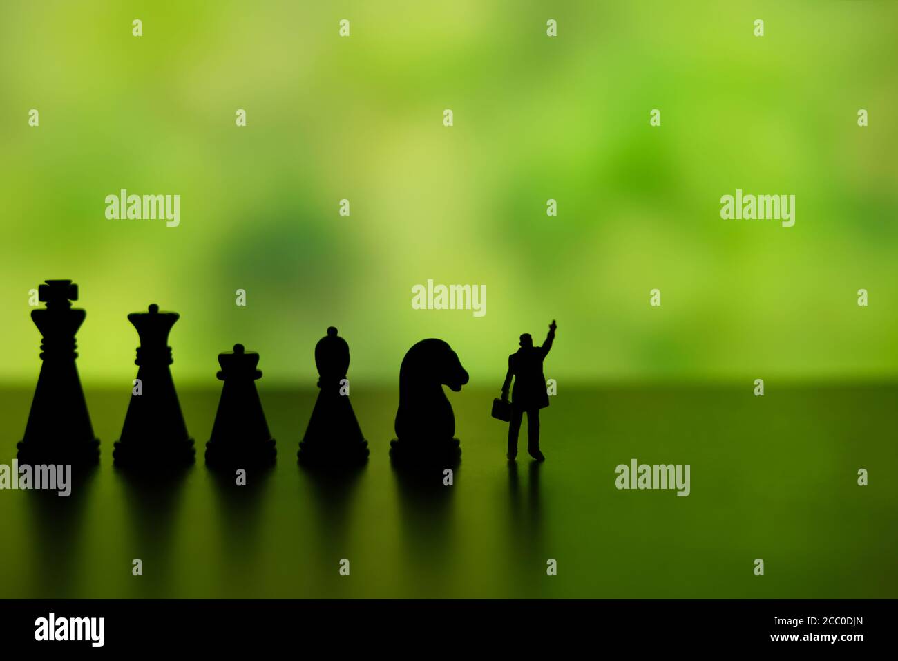 Business strategy conceptual photo - Silhouette of miniature businessman pointing upside, standing in front of chess piece row Stock Photo