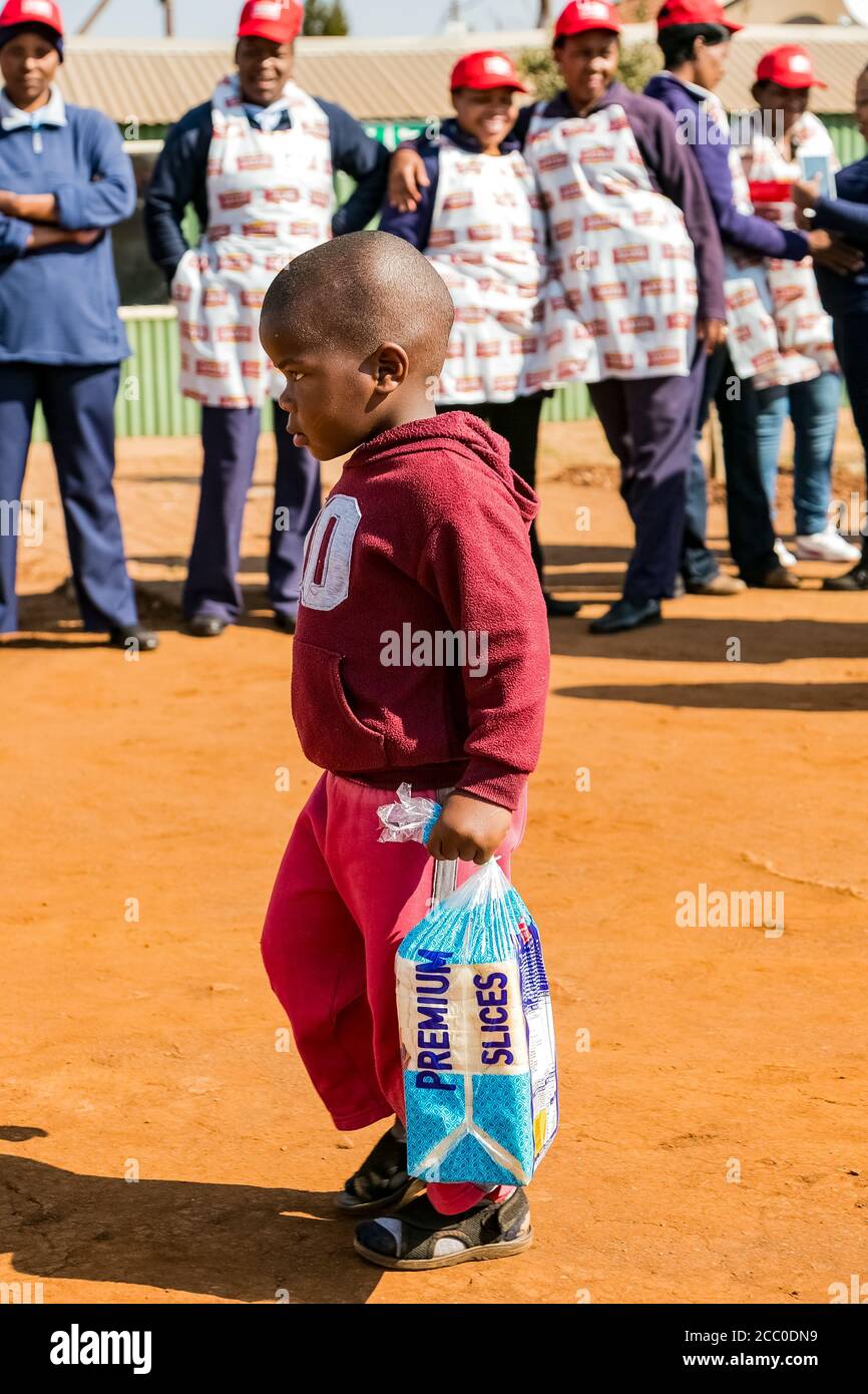 Soweto, South Africa - July 18, 2016: Young African Preschool kids running with a loaf of bread in the playground of a kindergarten school Stock Photo