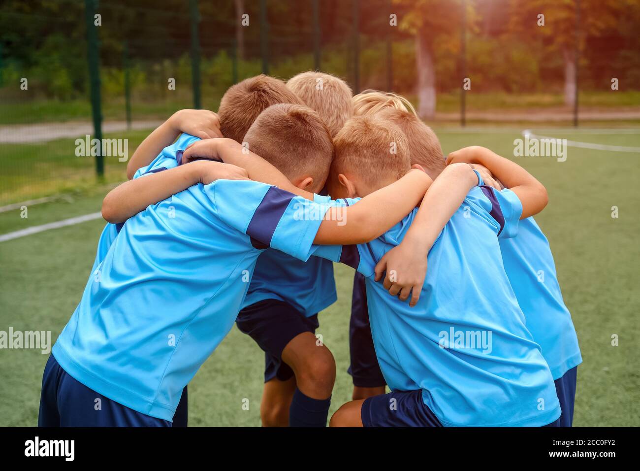 Kids football team embrace each other on football field before match  Stock Photo