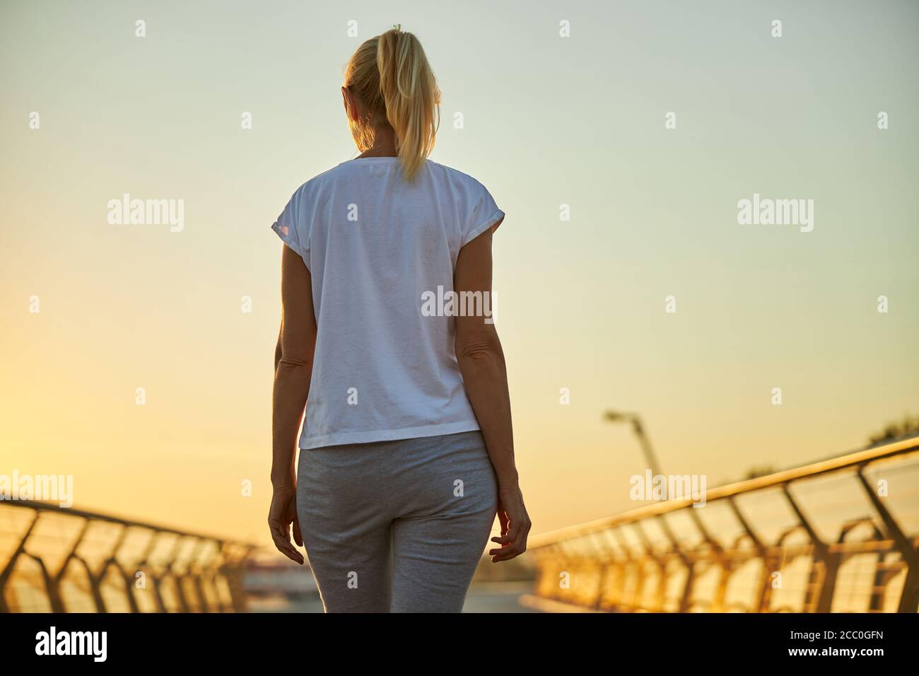 Blonde woman in white shirt standing on the bridge Stock Photo