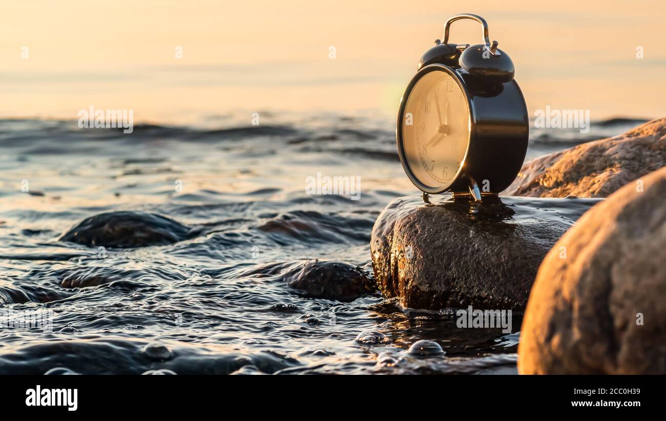 A clock that symbolizes the golden age of photography set up by the Swedish Baltic Sea during sunset when summer turns into autumn Stock Photo