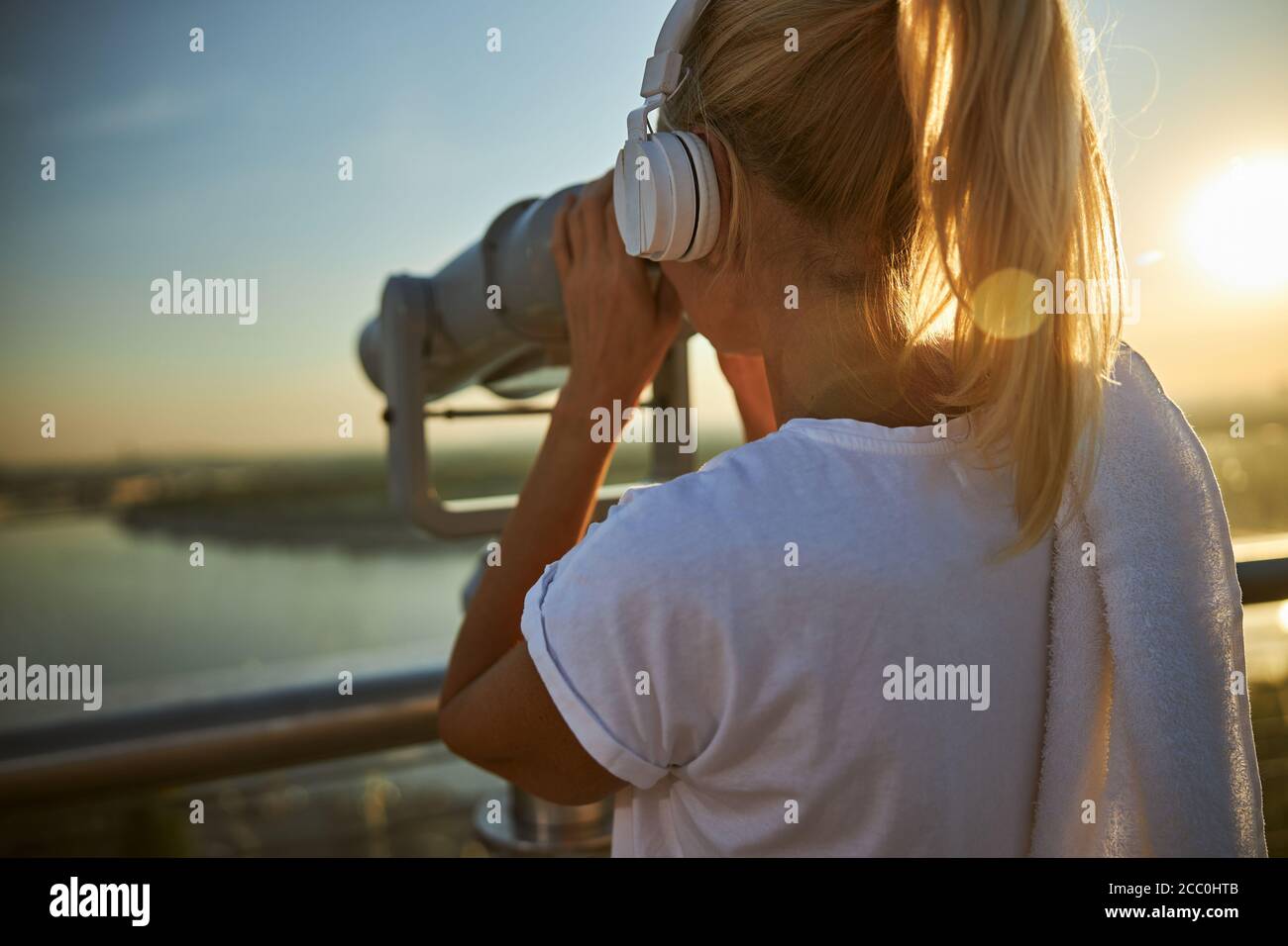 Woman in headphones using observation binoculars on the street Stock Photo
