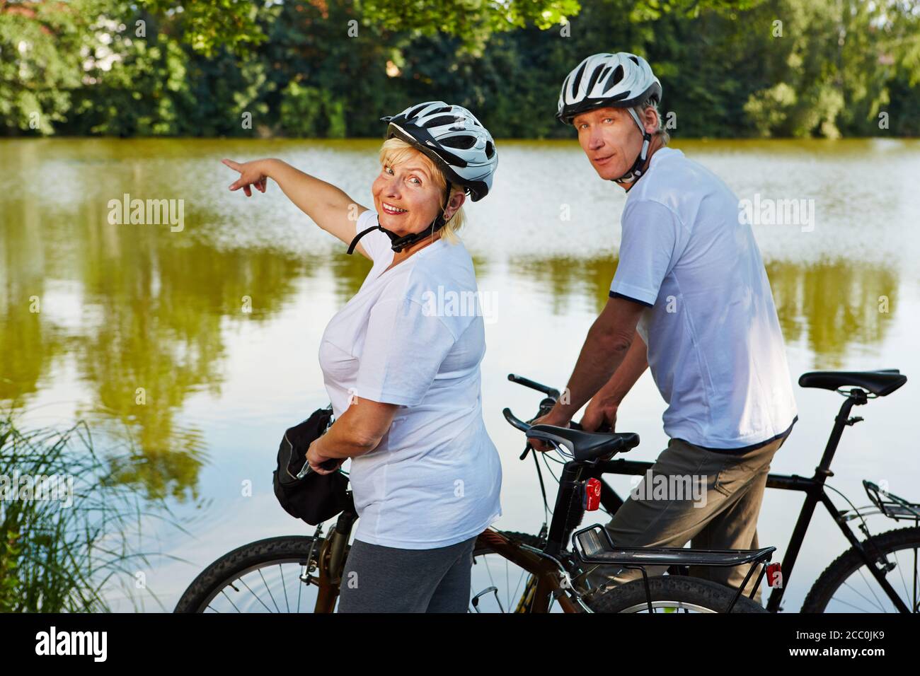 Two happy seniors go cycling in summer by bike Stock Photo