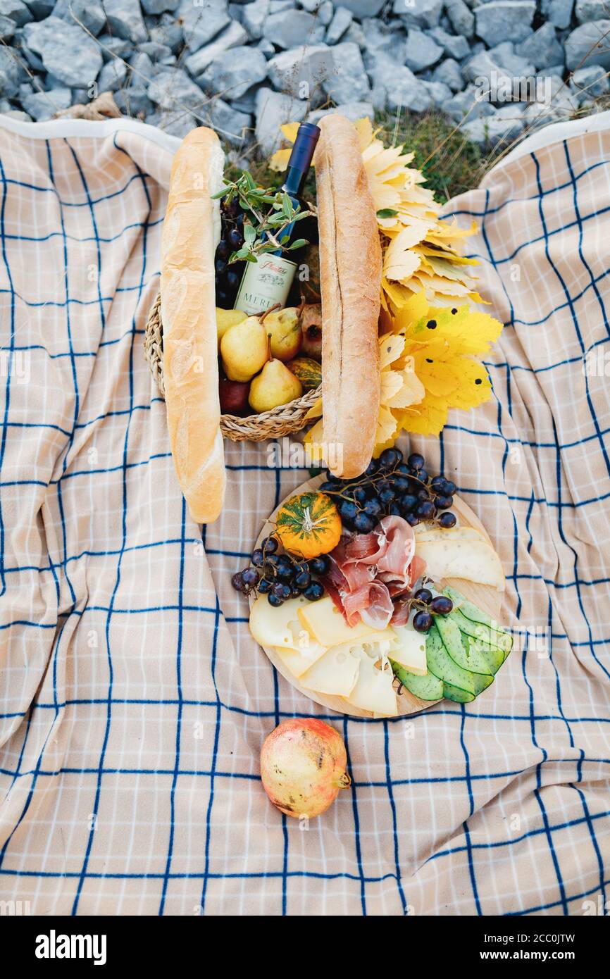 https://c8.alamy.com/comp/2CC0JTW/food-for-a-picnic-in-nature-on-a-fabric-bed-with-a-baguette-a-bottle-of-wine-fruit-and-cheese-and-cold-cuts-2CC0JTW.jpg