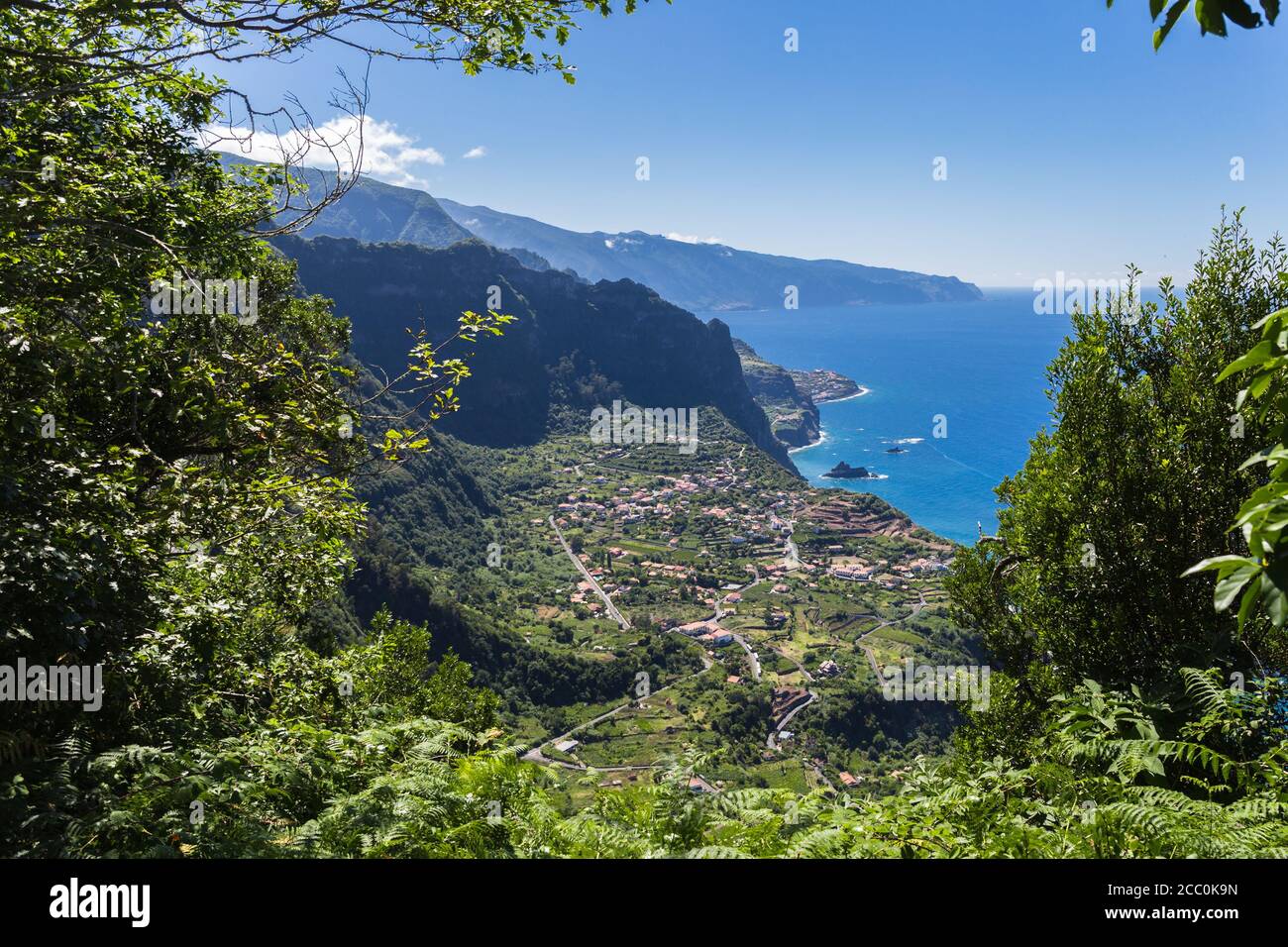 View of "Arco de Sao Jorge" village from "Cabanas" viewpoint through green folliage in Santana, Madeira island, Portugal Stock Photo