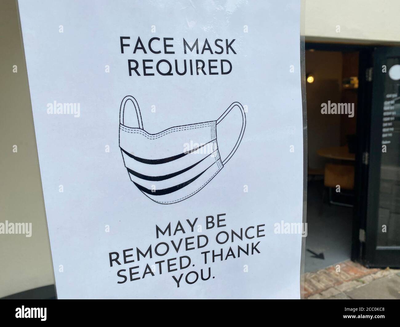 Protective face mask required sign outside a restaurant Stock Photo