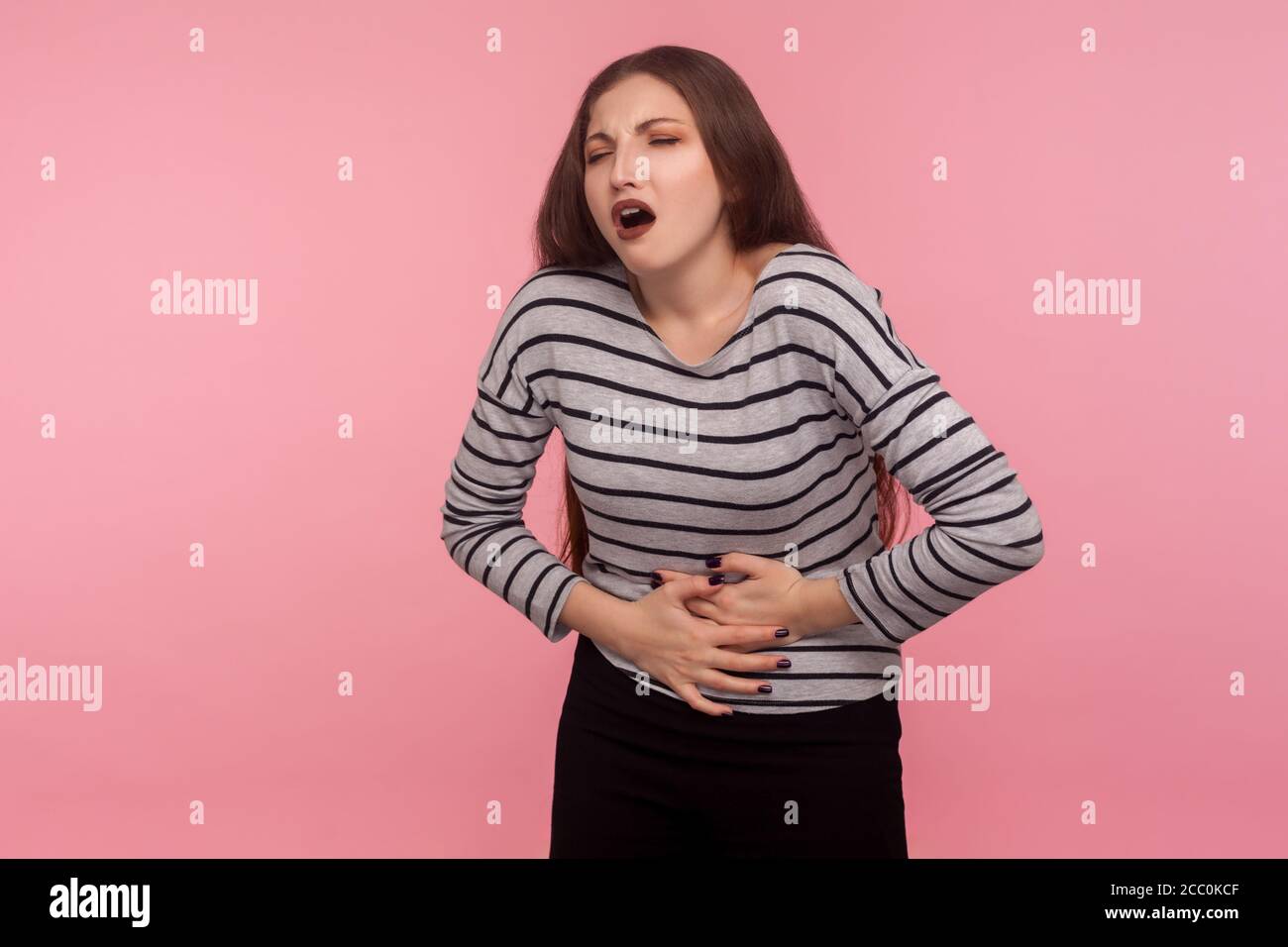 Stomachache. Portrait of unhealthy woman in striped sweatshirt clasping