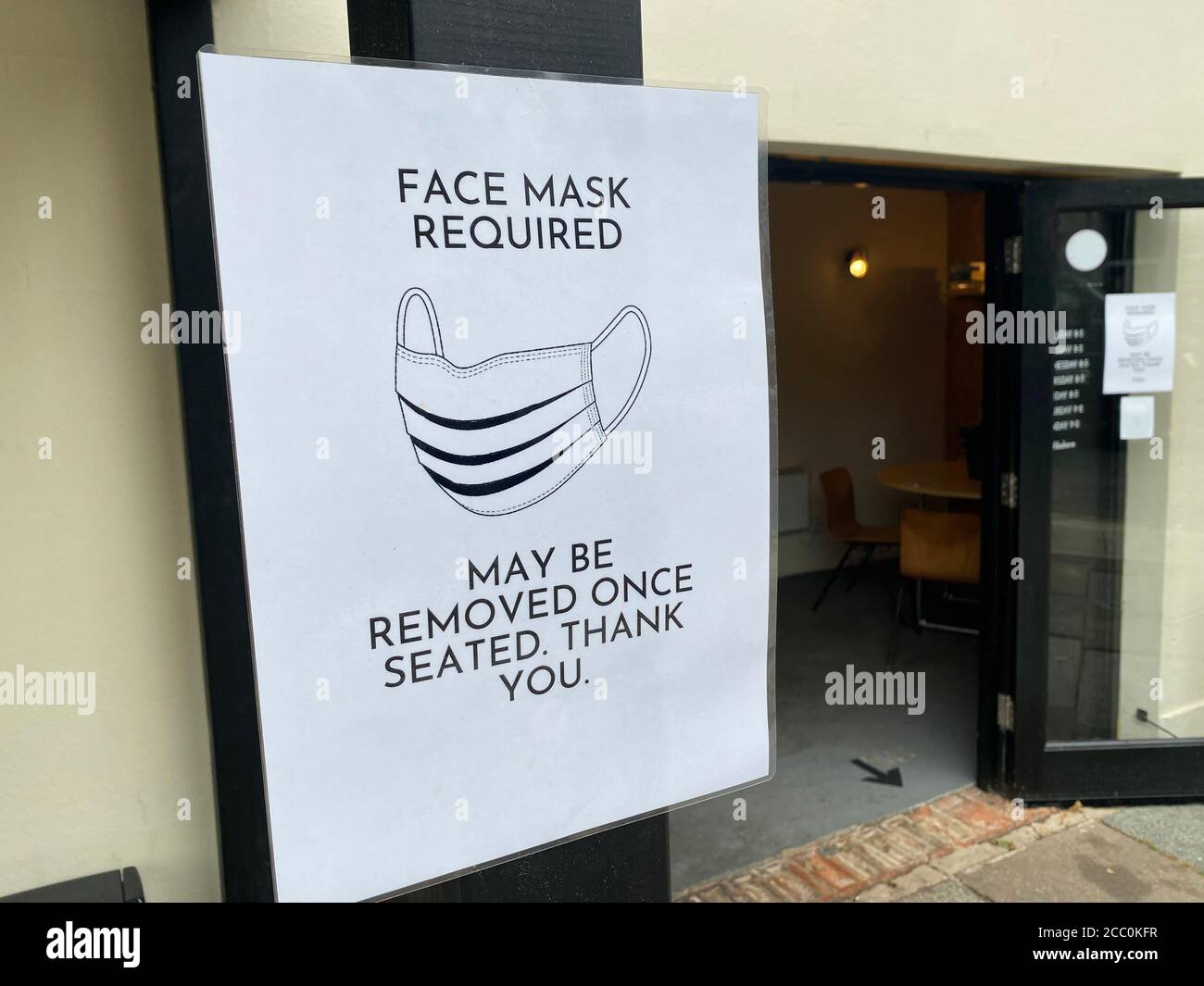 Protective face mask required sign outside a restaurant Stock Photo