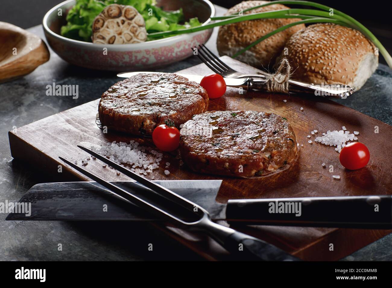 Raw Ground beef meat Burger steak cutlets with ingredients on the board. Stock Photo