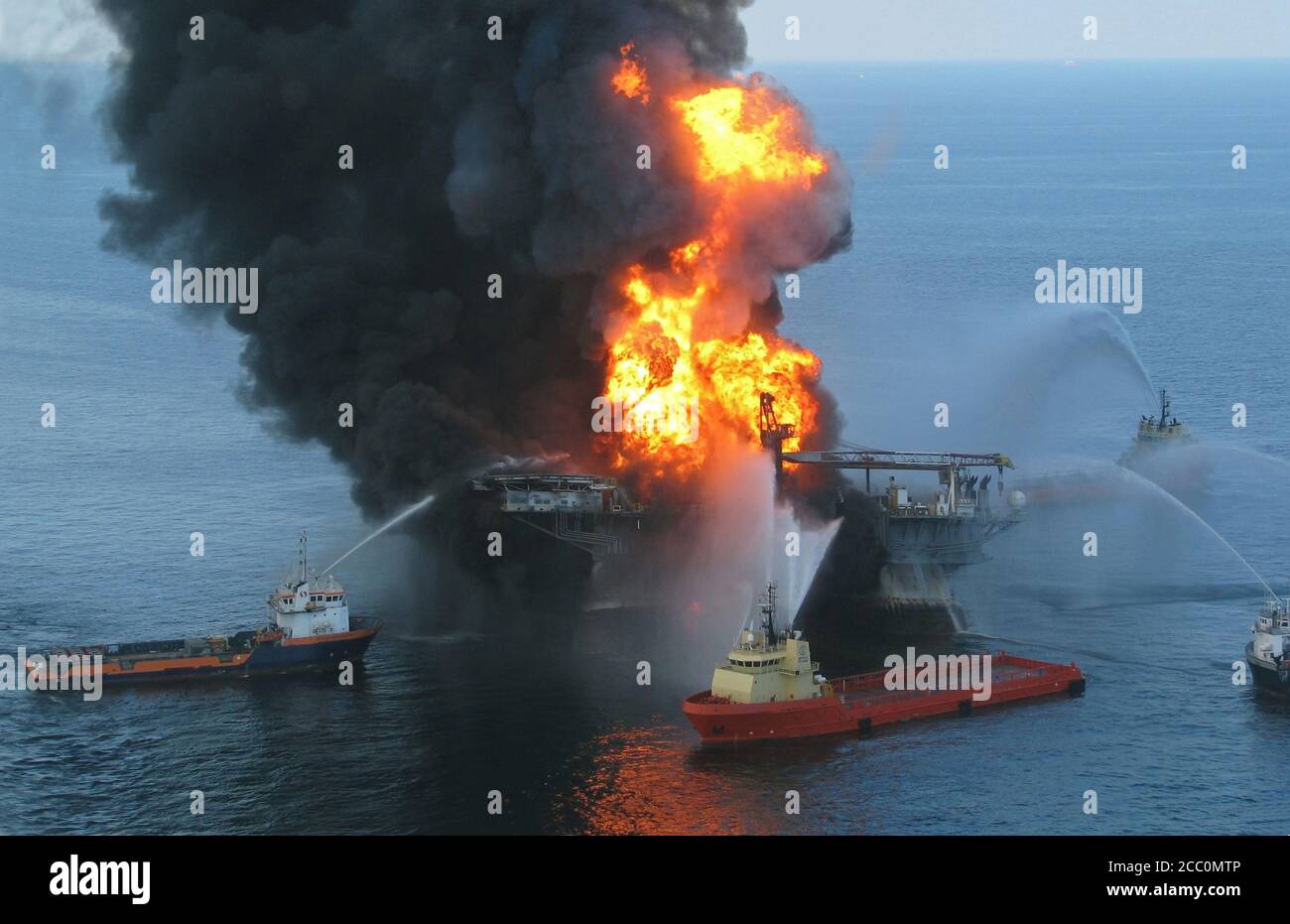GULF OF MEXICO, USA - 21 April 2010 - Platform supply vessels battle the blazing remnants of the off shore oil rig Deepwater Horizon. A Coast Guard MH Stock Photo