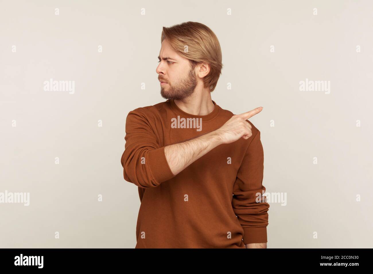 Leave me! Portrait of upset vexed man with beard in sweatshirt pointing finger aside, ordering get out and looking resentful, boss dismissing from wor Stock Photo