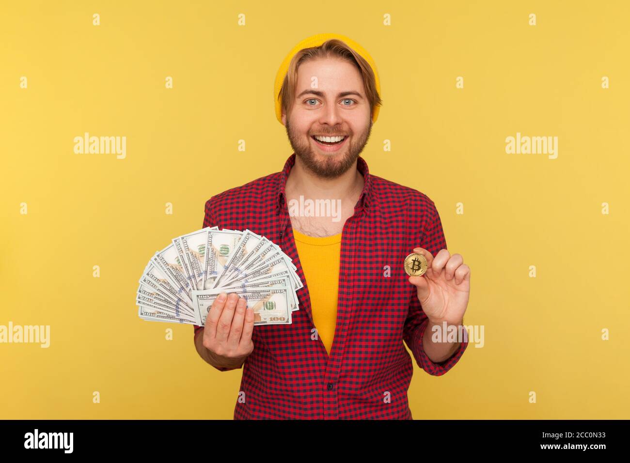 Digital investment, money exchange. Cheerful hipster guy in checkered shirt  holding dollar bills and bitcoin, btc coin cryptocurrency, smiling at came  Stock Photo - Alamy