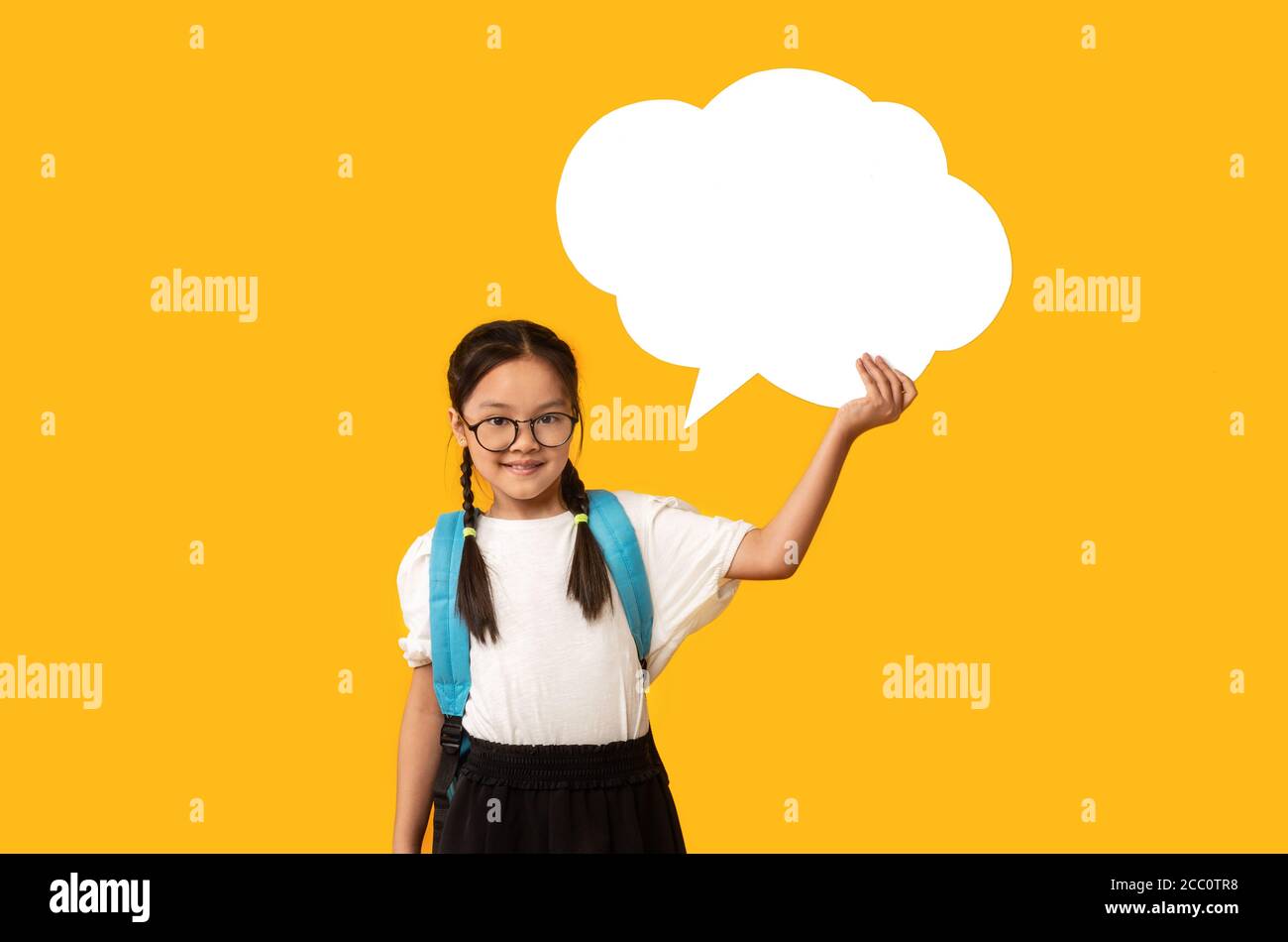 Cheerful Korean Schoolgirl Holding Blank Thought Bubble, Yellow Background, Mockup Stock Photo