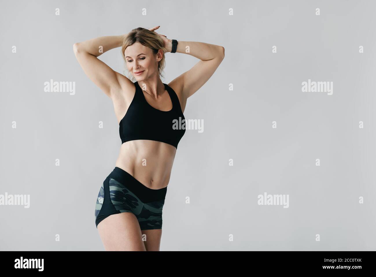 Slender figure. Happy woman with smart watch demonstrates biceps and muscular body Stock Photo