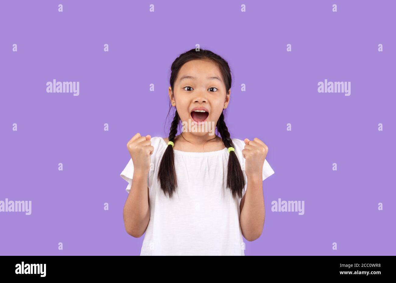 Joyful Korean Girl Shaking Fists Over Purple Background, Studio Shot Stock Photo