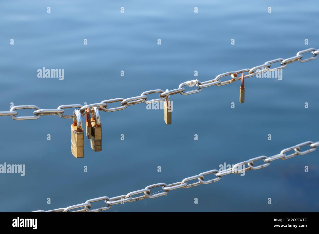 Love padlocks hanging on metal chain fence Stock Photo