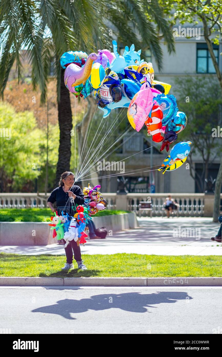 BARCELONA, SPAIN - Apr 13, 2015: Barcelona / Spain - April 12 2015: Female  Street Vendor Sells Animal Shaped Baloons in the Grass in a Public Park whi  Stock Photo - Alamy