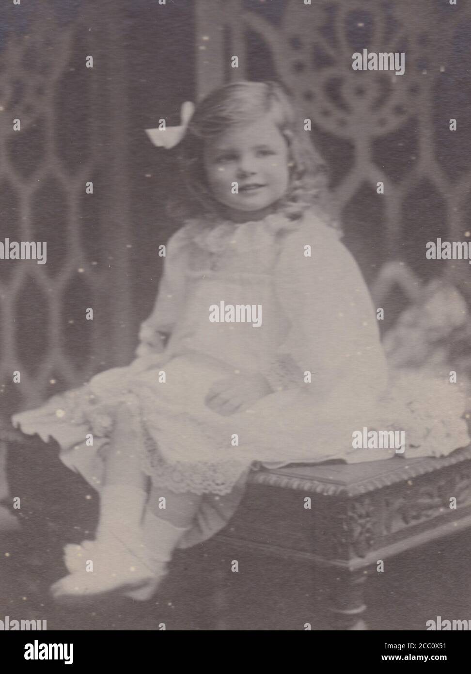 Vintage black and white photo of a cute little girl wearing a dress and bow in her hair 1900s Stock Photo