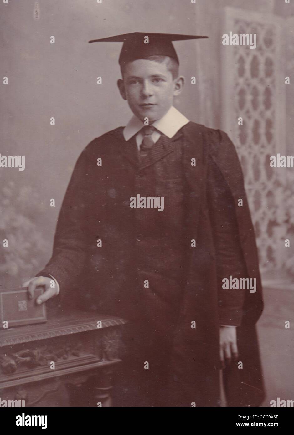 Vintage black and white photo of young boy wearing mortar board hat and gown - Private School / University 1900s Stock Photo