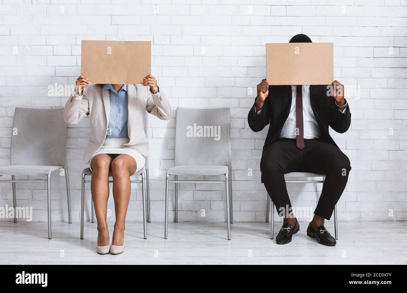 African American job applicants closing their faces with blank signs at company office, space for design Stock Photo