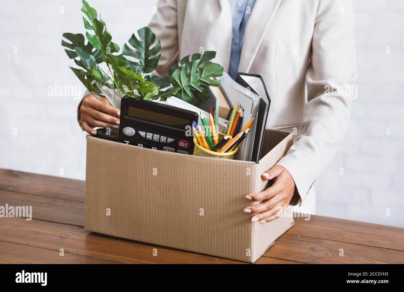 Economic crisis and unemployment. Unrecognizable black girl with box of belongings at table in office Stock Photo