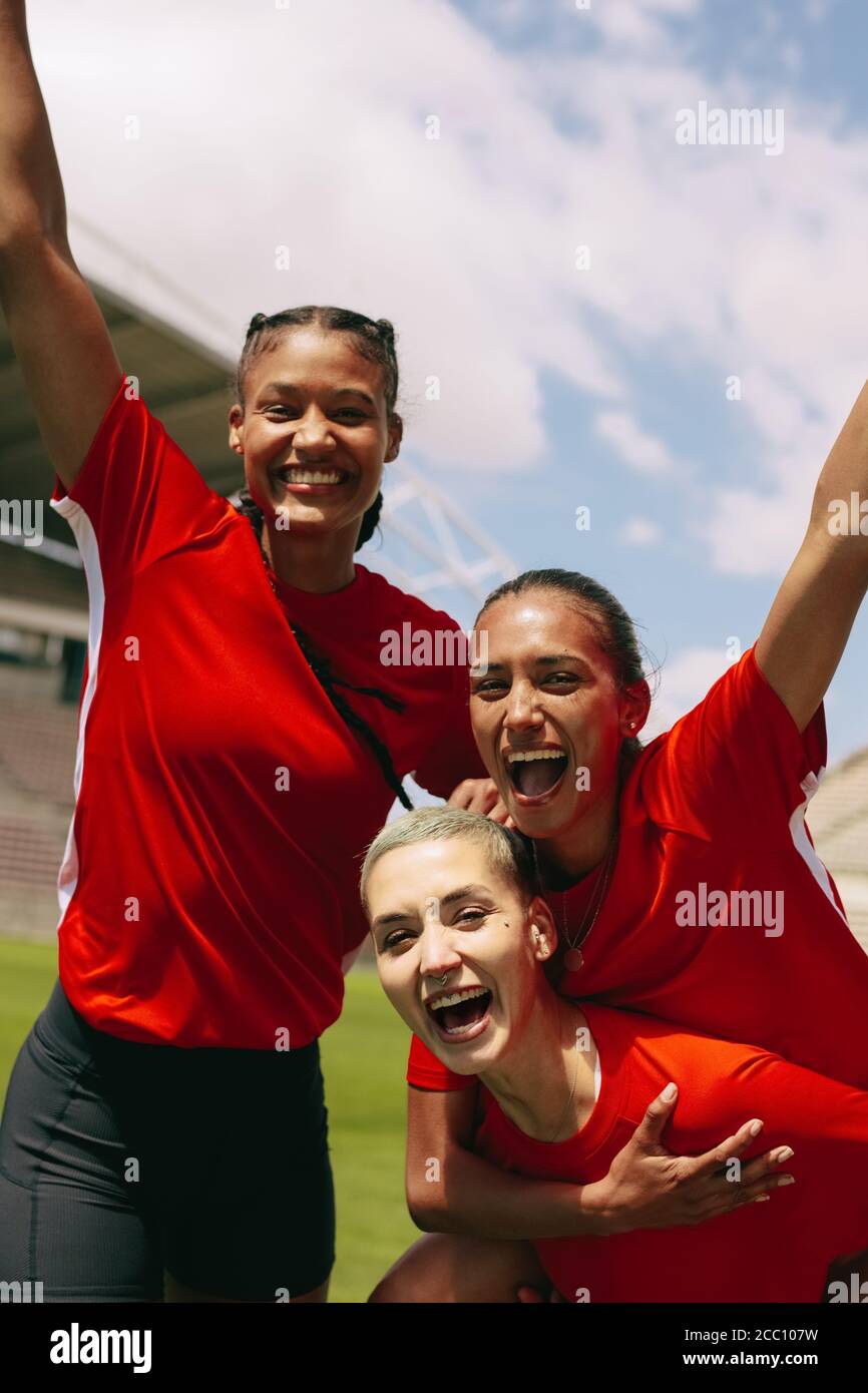 Soccer players on field shouting after winning the match. Female soccer team celebrating success. Stock Photo