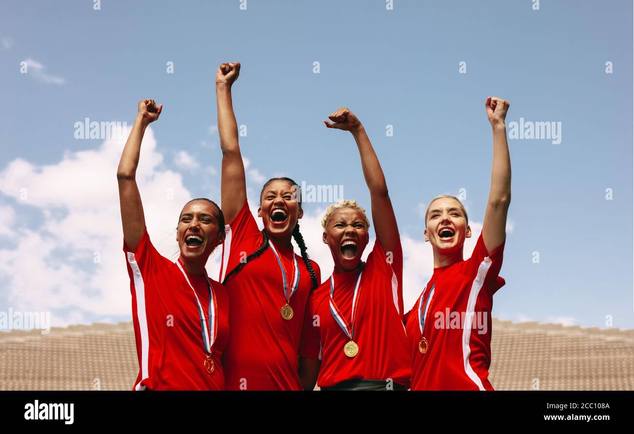 Professional female soccer players celebrating a victory on a sports arena. Group of woman