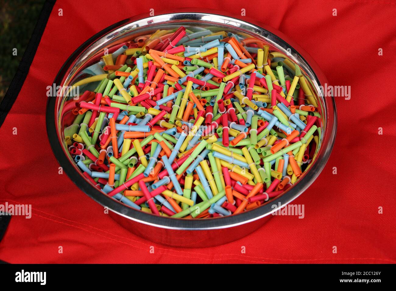 Closeup of colorful tombola tickets in a bowl on a red background Stock Photo