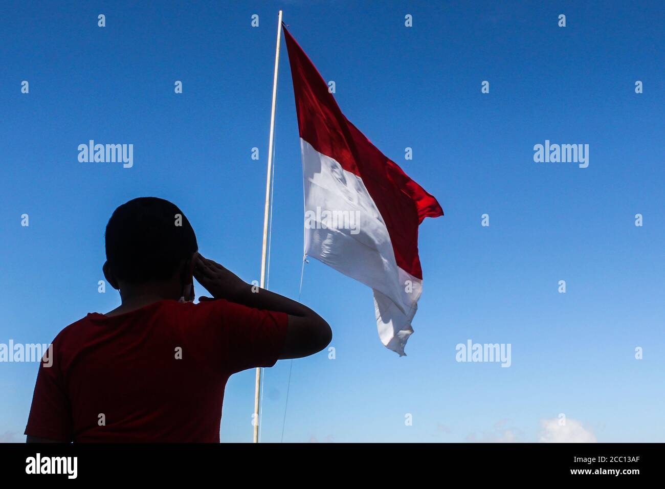 Sleman, YOGYAKARTA, INDONESIA. 17th Aug, 2020. An Indonesian child salutes the Red and White Flag when marking the 75th anniversary of the independence of the Republic of Indonesia in Cangkringan, Sleman, Yogyakarta, Indonesia, Monday, 17 August 2020. Indonesia became independent in 1945 from Dutch colonialism. Credit: Slamet Riyadi/ZUMA Wire/Alamy Live News Stock Photo