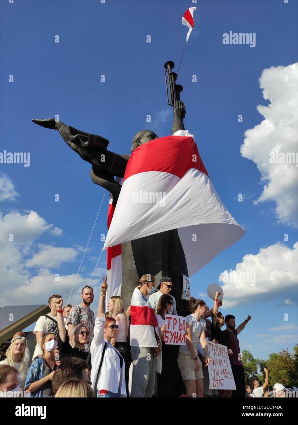 Minsk / Belarus - August 16 2020: Demonstrators standing at the foot of Motherland statue covered with white-red-white flag Minsk Hero City Obelisk Stock Photo