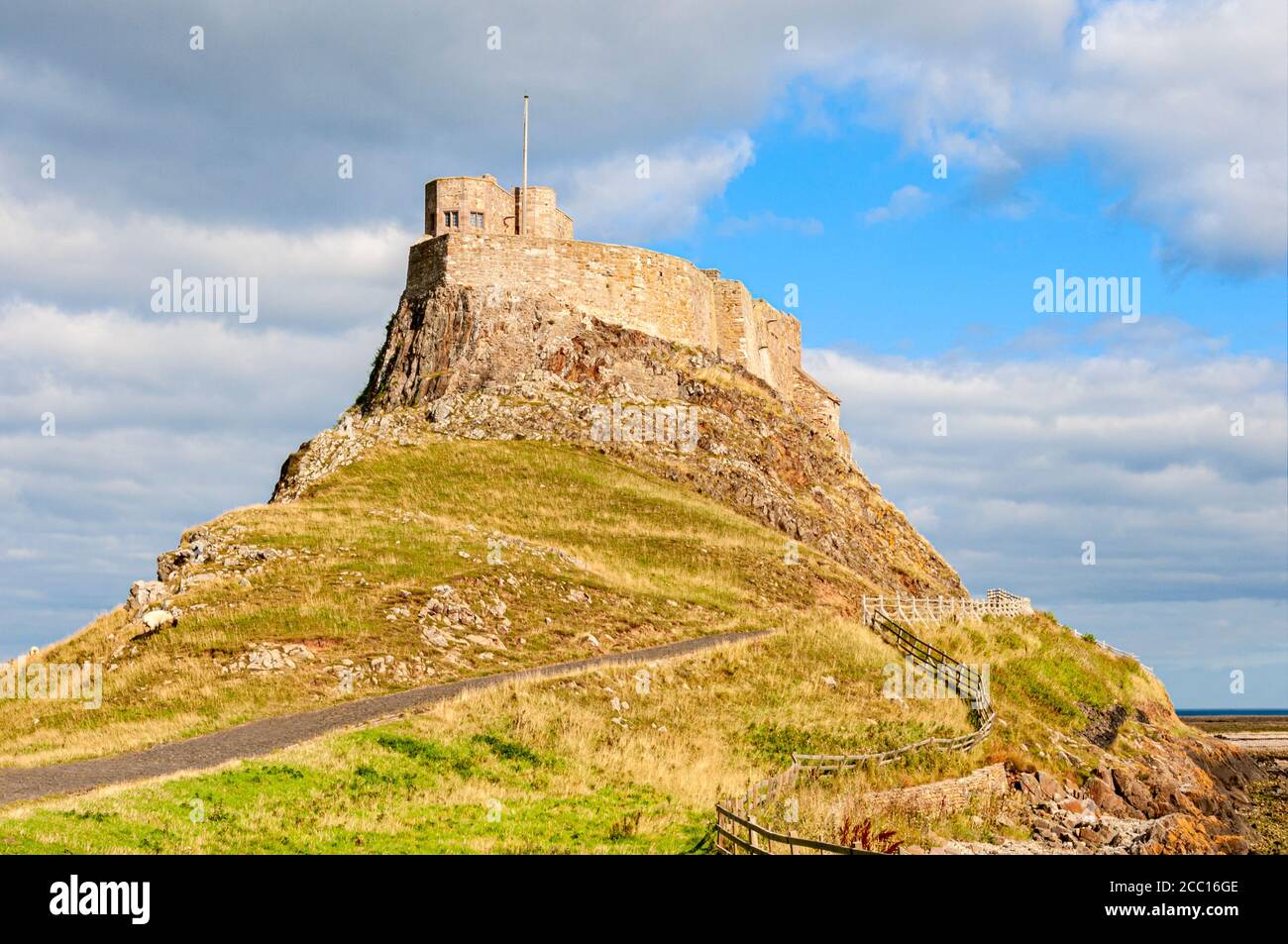 Sheep graze below the small 16th century castle modified by Sir Edwin Lutyens in 1901 sitting on the summit of the steep grass covered  Beblowe hill Stock Photo