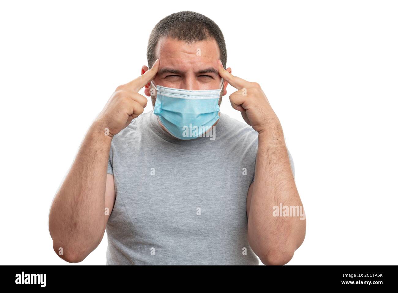 Male model wearing medical or surgical protection mask touching temples forehead as covid19 flu sars infection symptom migraine concept isolated on wh Stock Photo