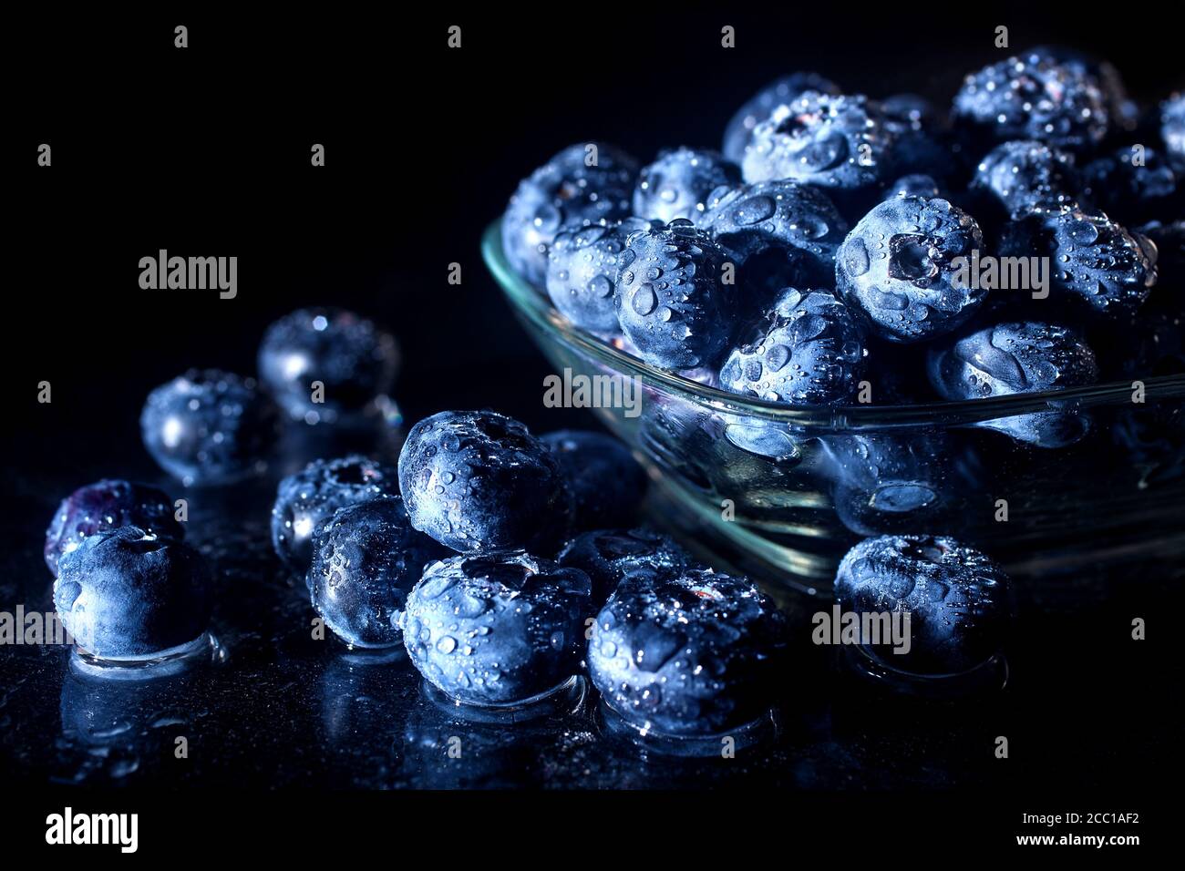 Freshly picked blueberries in a glass jar. Fresh and healthy juicy blueberries on a dark background. Blueberries as a fruit antioxidant symbol. Stock Photo