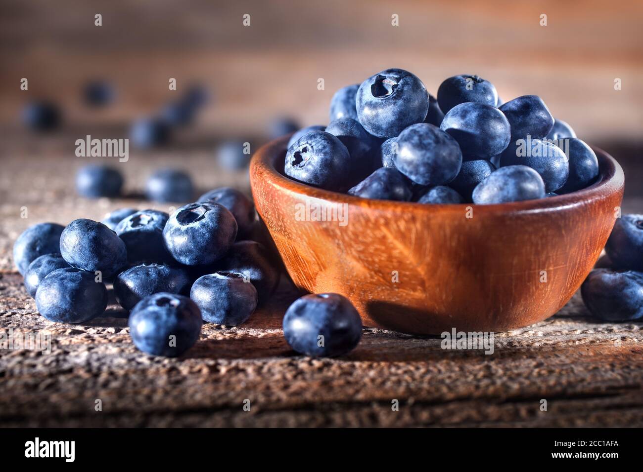 Freshly picked blueberries in a bowl. Fresh and healthy juicy blueberries on a rustic background. Blueberries as a fruit antioxidant symbol. Stock Photo