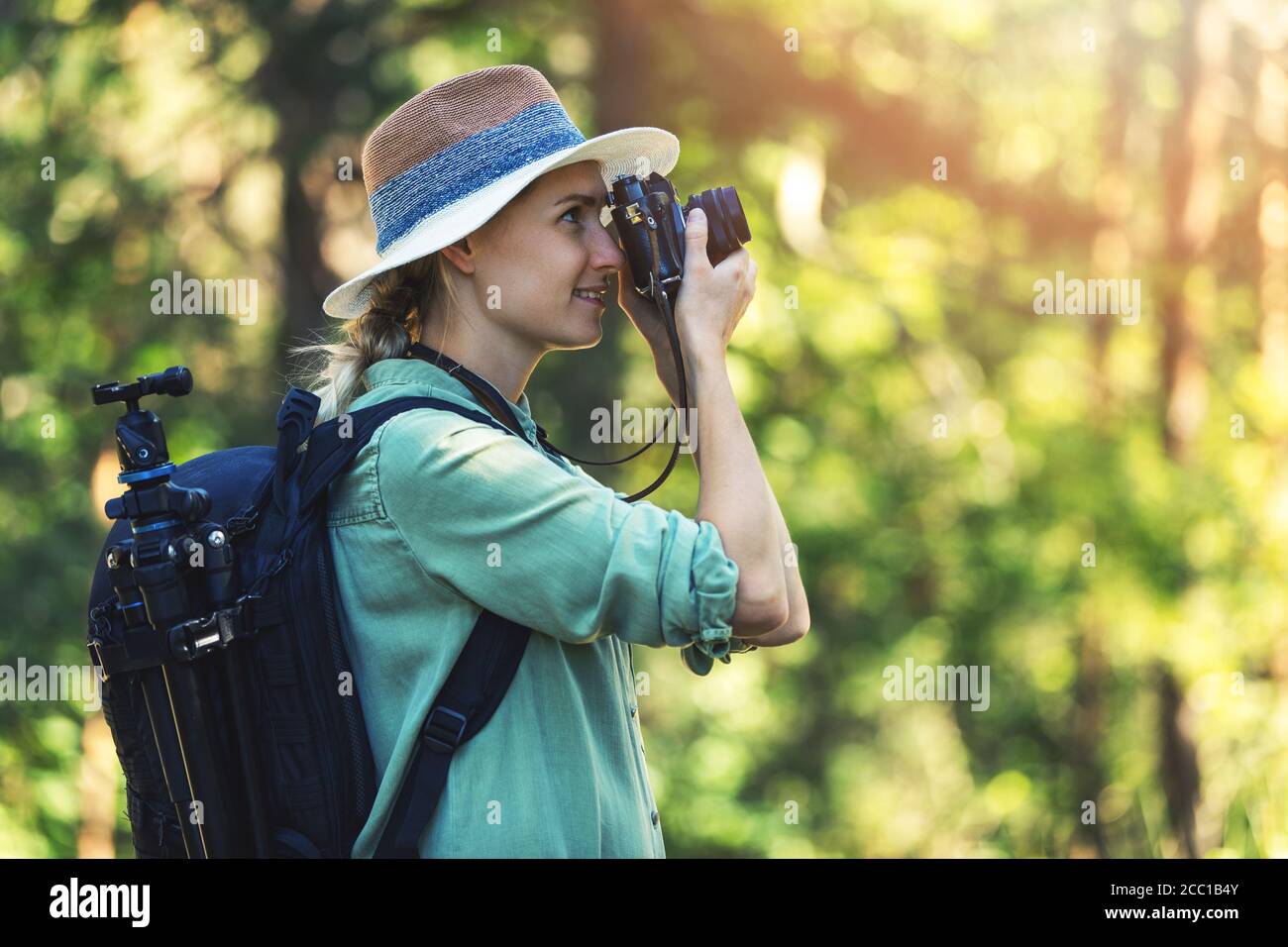 woman photographer taking picture of nature with analog film camera in forest Stock Photo