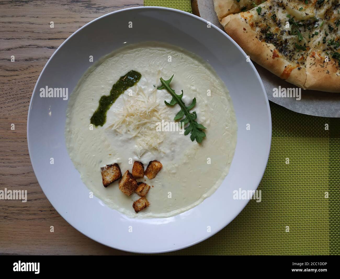 CHEESE CREAM SOUP WITH CRUTONS. In a deep plate, sprinkled with parmesan, a sprig of greens Stock Photo