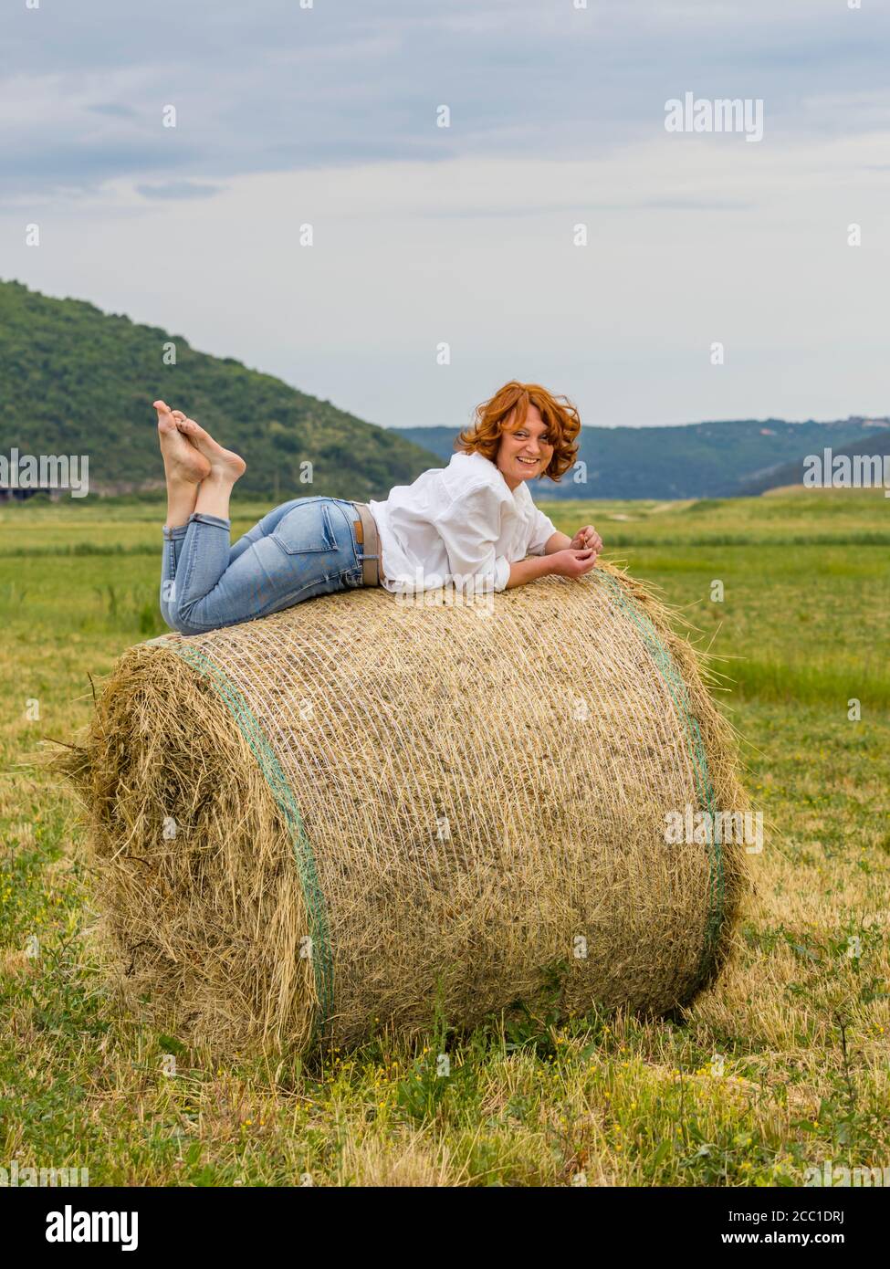 Mature woman on hay haystack in field Stock Photo