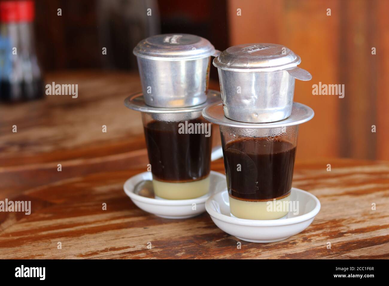 Traditional Vietnam coffee with sweeten condensed milk on wooden table background. Drip black coffee in Vietnamese style . Stock Photo