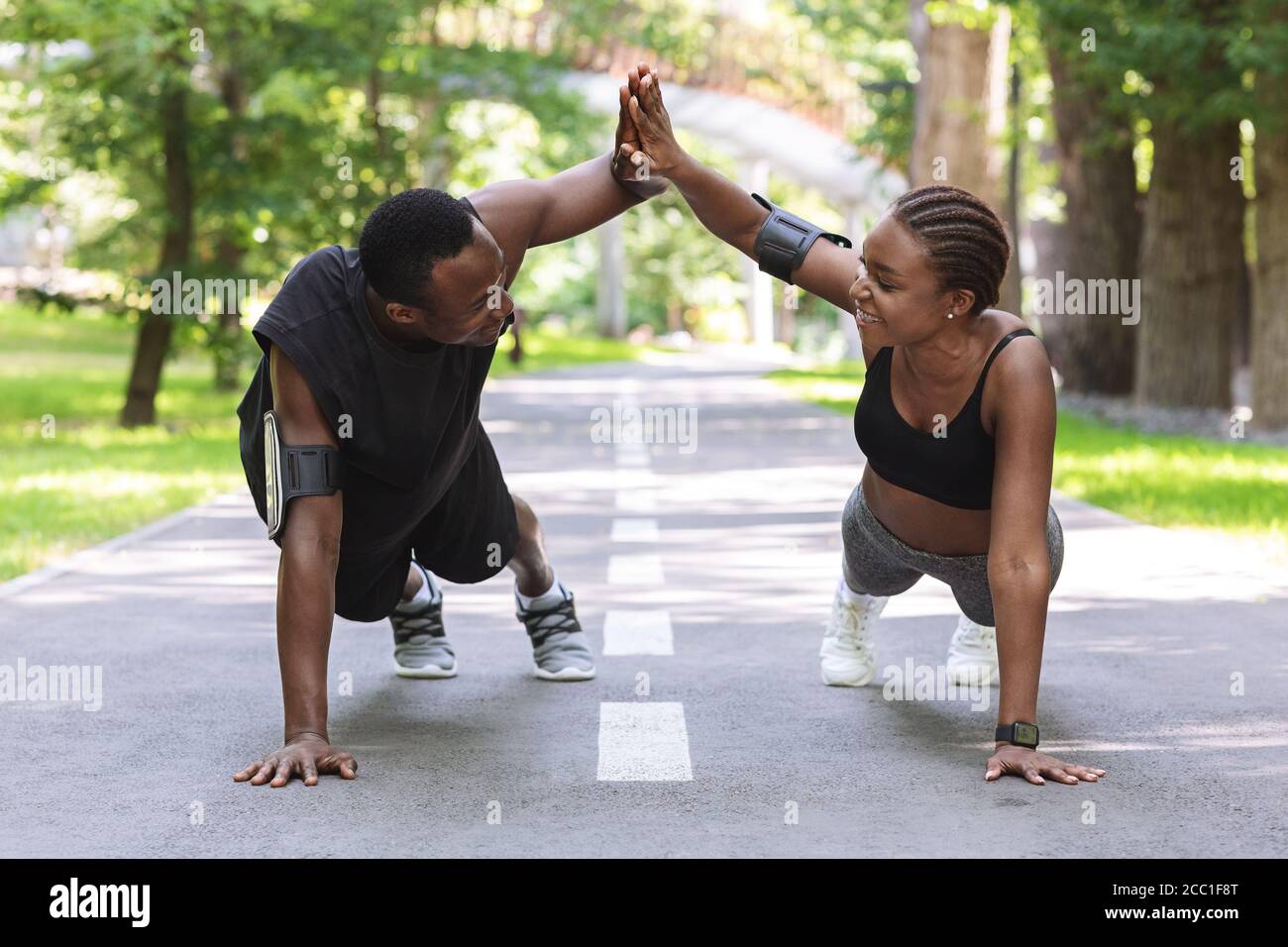 Motivated black couple giving high-five to each other while working out outdoors Stock Photo